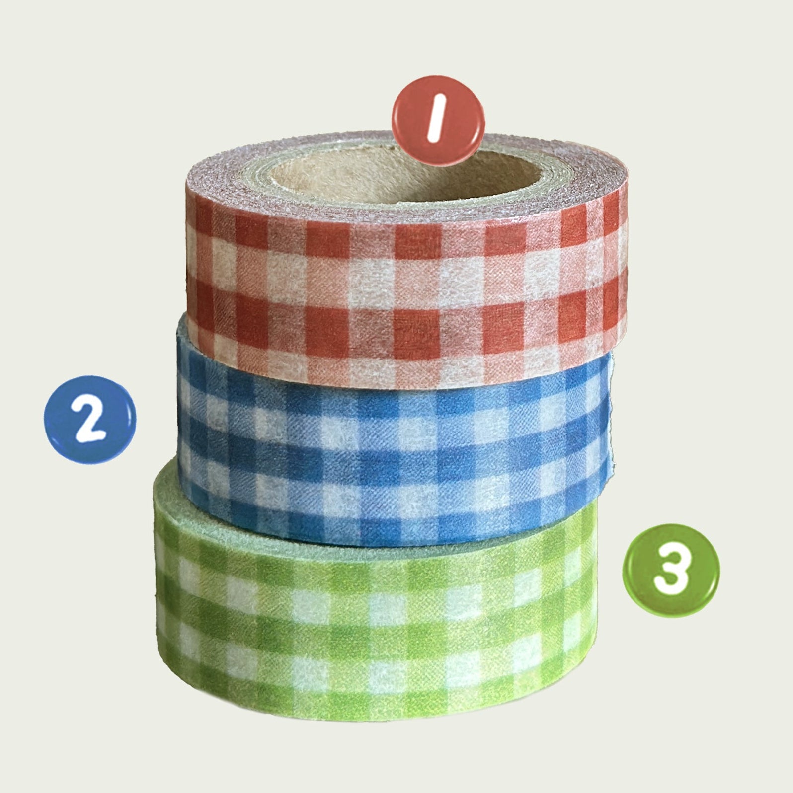 Three rolls of plaid masking tape stacked on a light gray background with decorative elements.